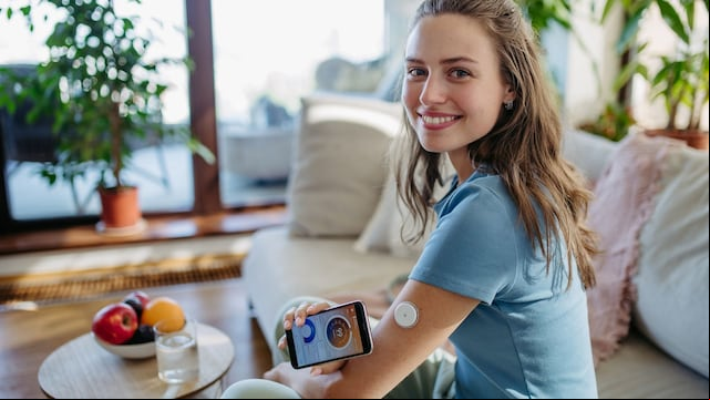 mujer con un dispositivo en el brazo para medir sus niveles de glucosa con el móvil